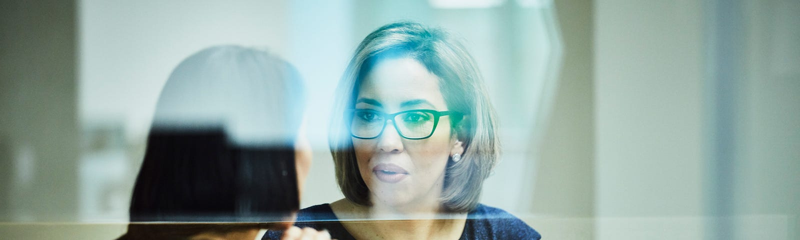 A photo of a mixed-race woman in a business meeting with another woman.