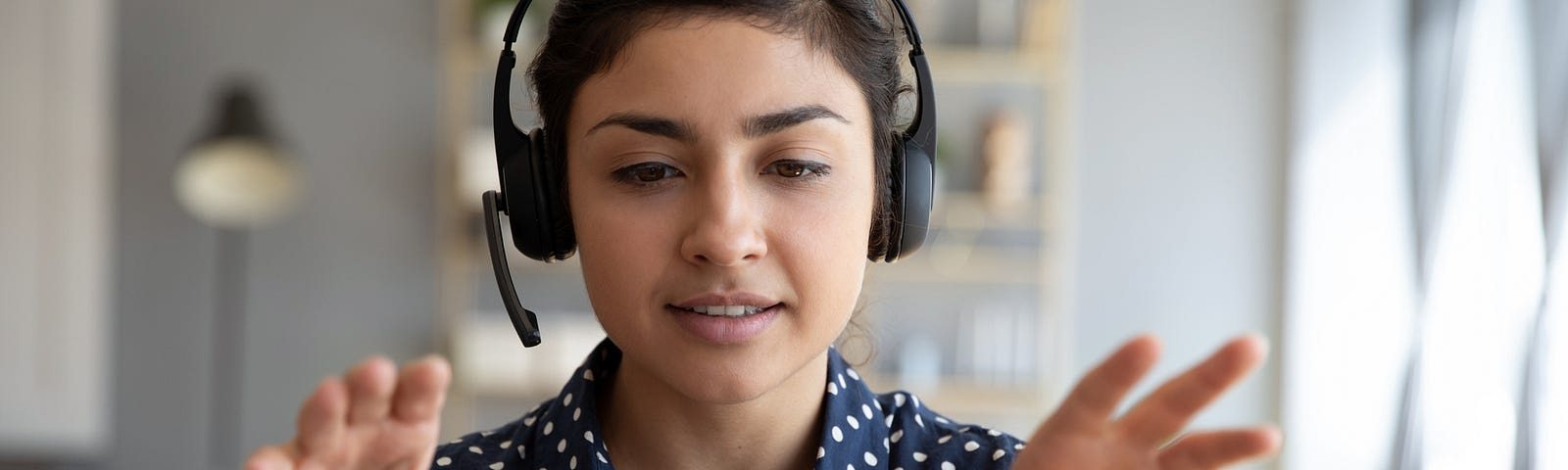 A photo of a South Asian woman talking on the mic on a video conference call.