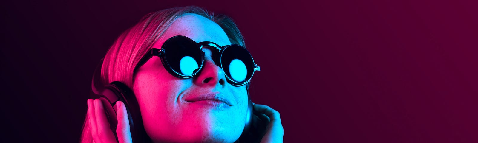 A photo of a girl with sunglasses and headphones on, with neon pink/blue lighting.