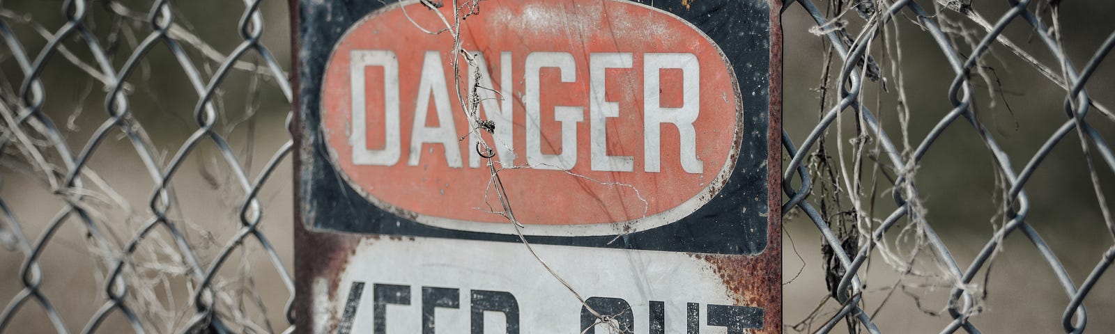 A sign on a wire fence that says “DANGER KEEP OUT.”