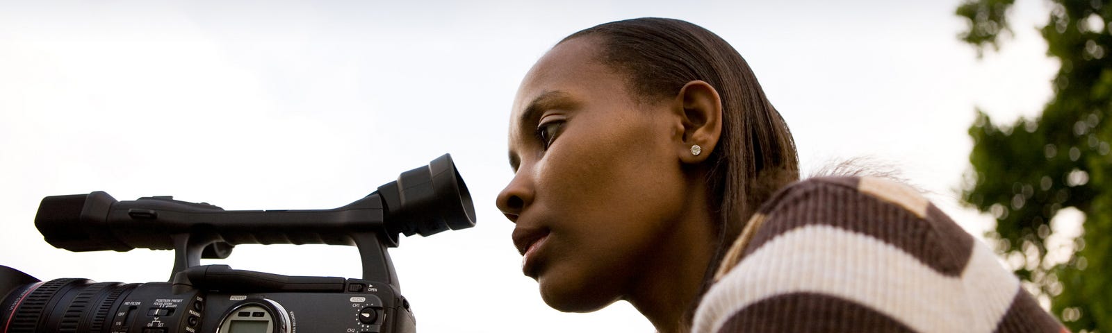 Black female journalist recording on her video camera.