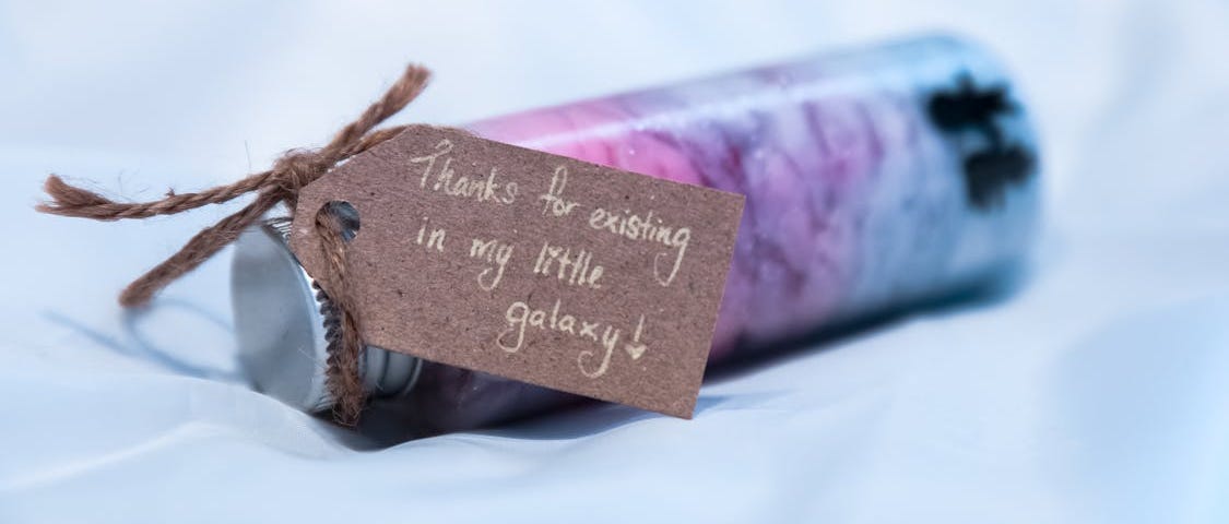 Thank You note that says “Thanks for existing in my little galaxy” attached to a small, colorful bottle