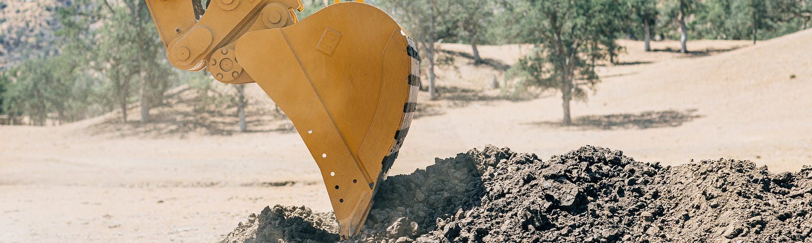 Picture of a back hoe with a bucket, digging up dirt.