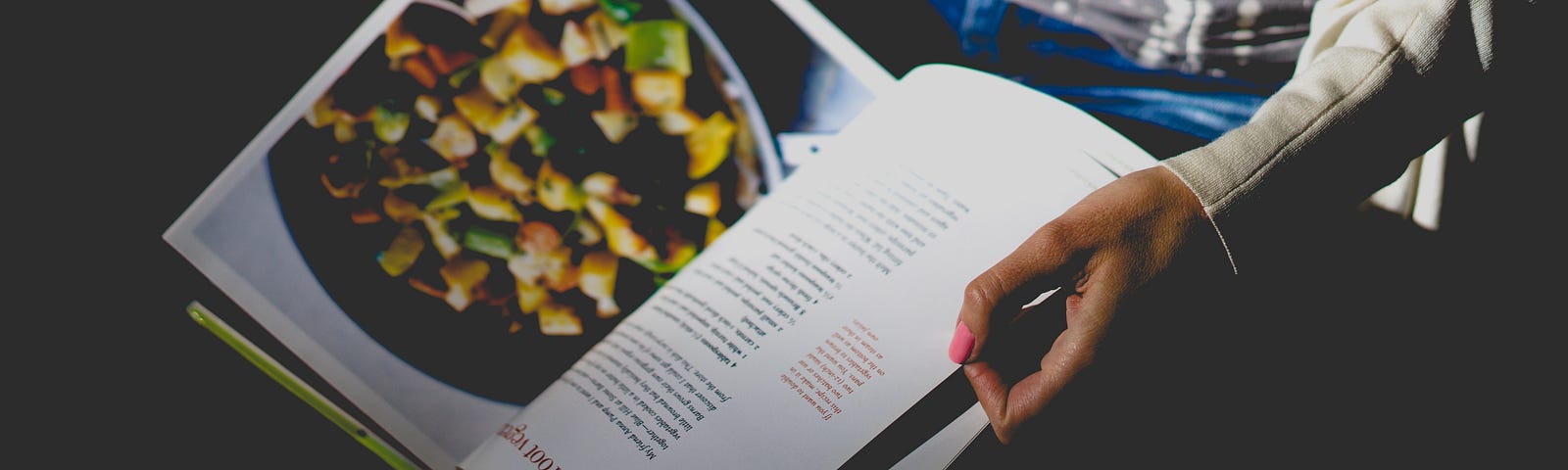 A person’s hands holding open a cookbook.