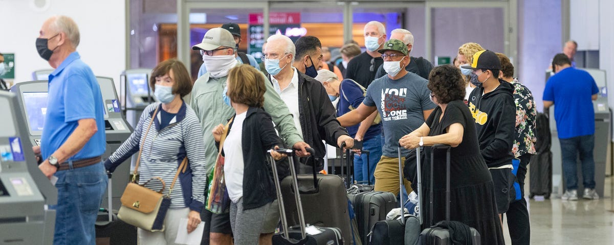 Travelers wait at John Wayne Airport in Santa Ana, California, on June 30.