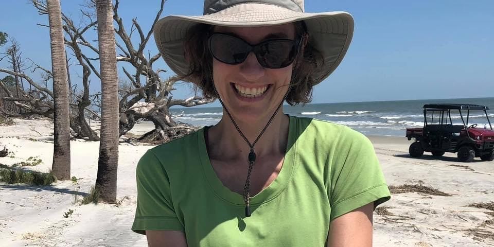 a woman on the beach holds sea turtle hatchlings