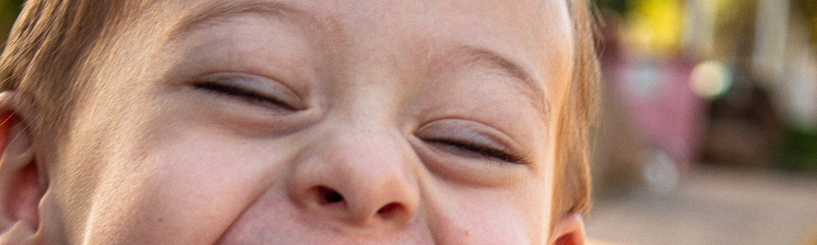 small blonde boy laughing really hard at the camera