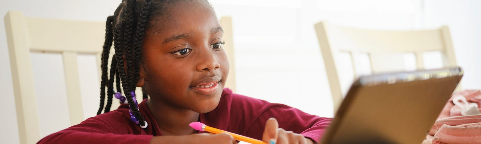 Young Black girl doing homework at home as part of remote learning.