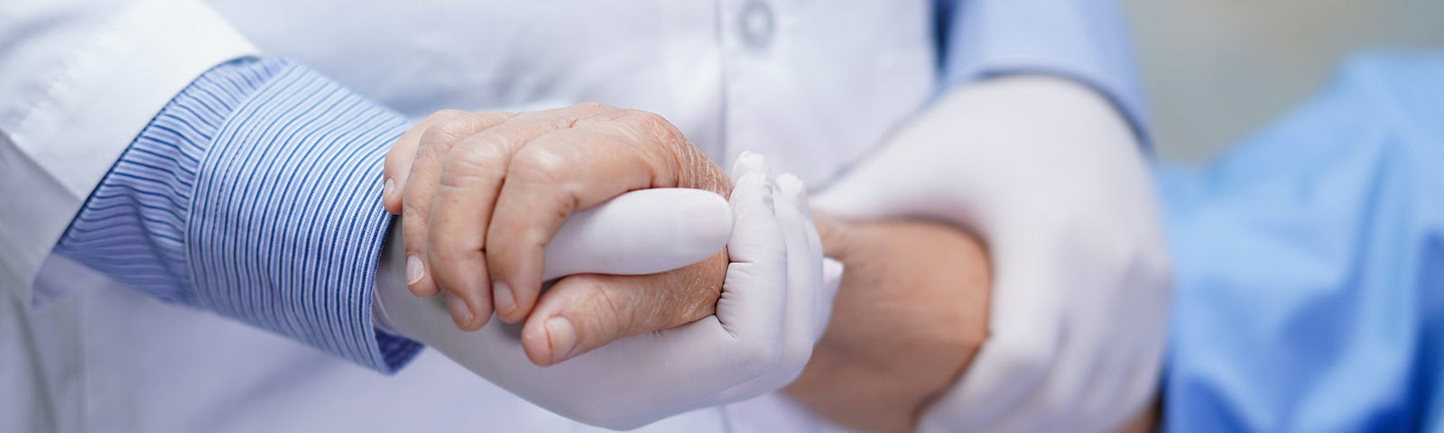 A photo of a patient holding a nurse’s gloved hand.