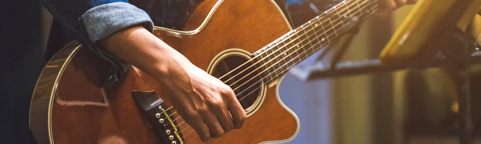 A person playing an acoustic guitar on a stage