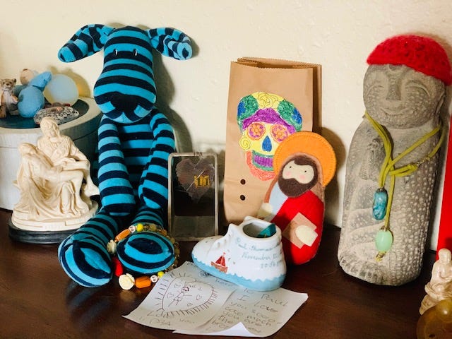 A Pietá figurine, striped dog plushie, letter from a child, and other personal items.