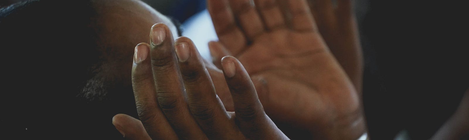 Black woman raising her hands in prayer.