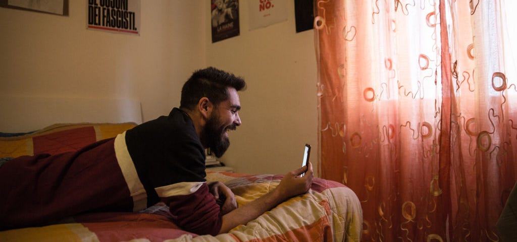 A photo of a young man video calling his grandpa in his room.