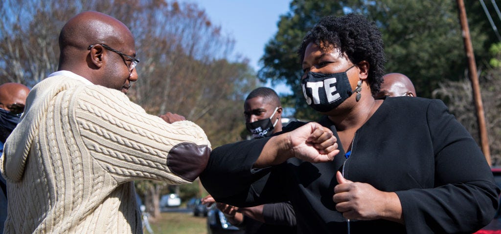 Reverend Raphael Warnock and Stacey Abrams bump elbows.