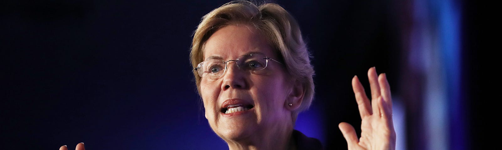 A photo of Elizabeth Warren with her hands raised.