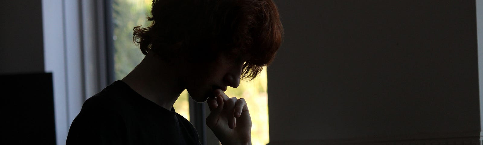 Dark image of a boy on his laptop.