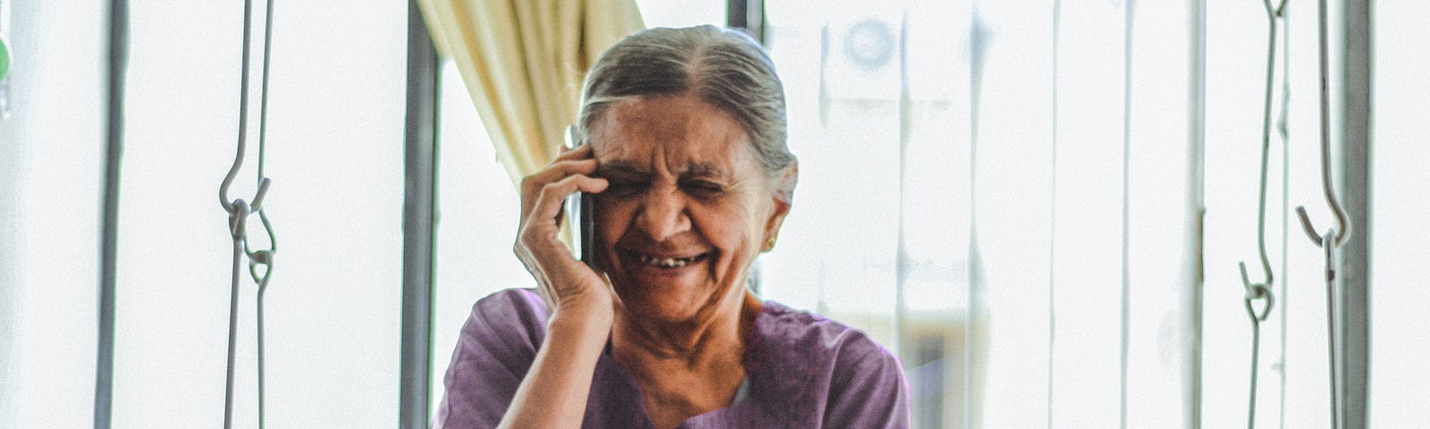 A grandmother smiles and laughs as she talks on the phone.