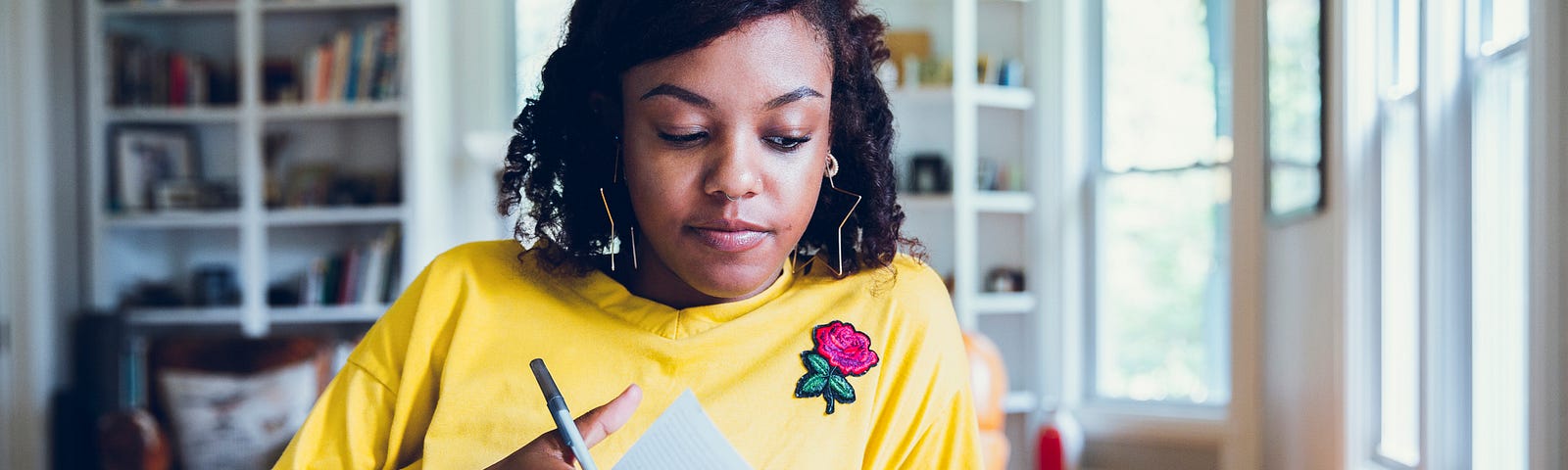 Young Black woman writing in her journal.