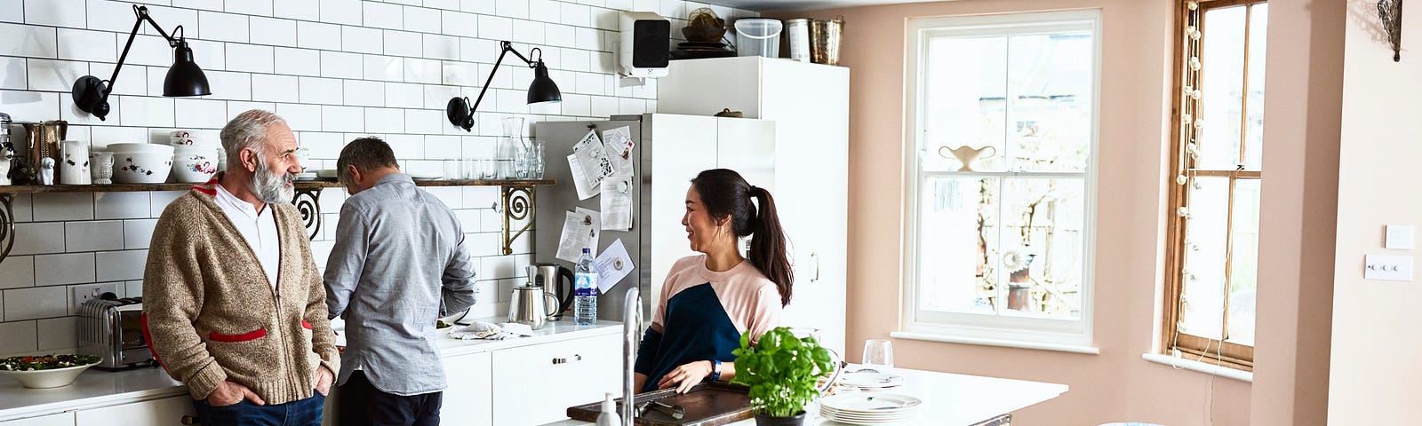 A photo of an Asian woman in the kitchen with her white husband and father-in-law.