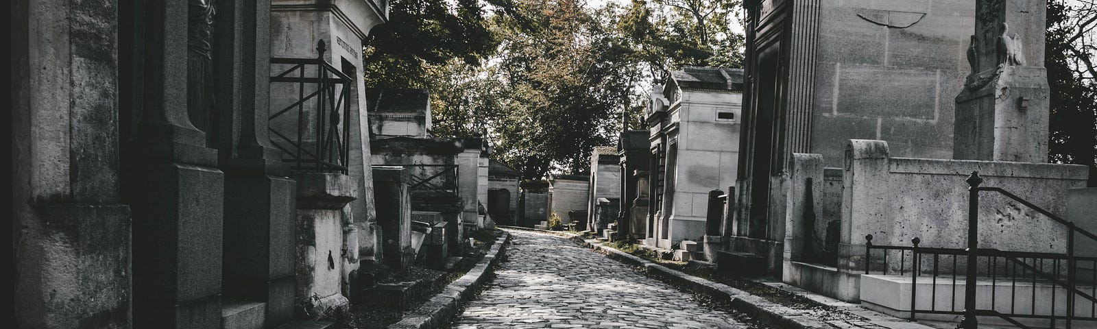 A darkish image of a cobblestone path to a graveyard.