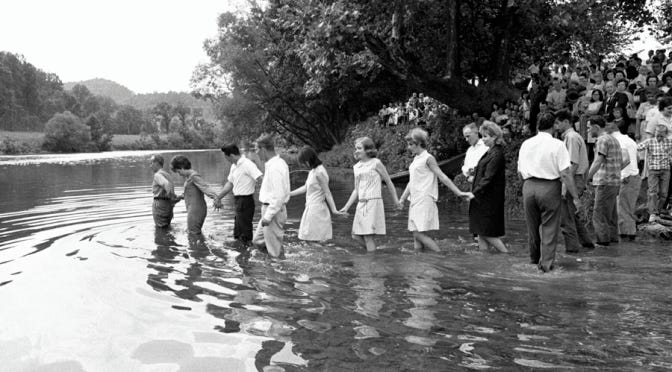 Mid-century children wade into the local river for a group baptism.