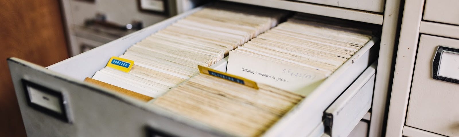 A filing cabinet with an open drawer with many index cards inside.