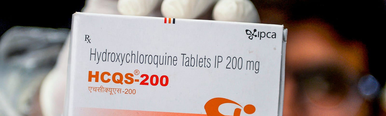 A pharmacist displays a box of hydroxychloroquine tablets.