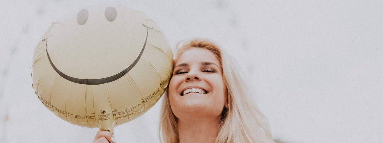Happy woman holding a smiling face balloon