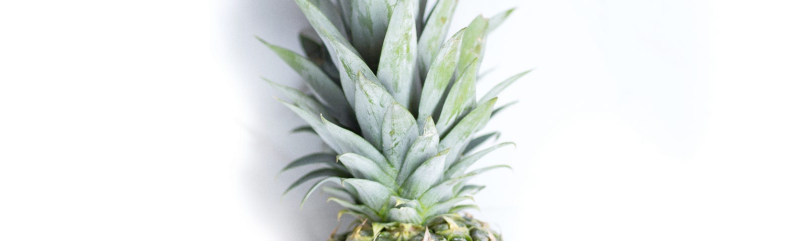 A pineapple with round sunglasses on it, on a white background.