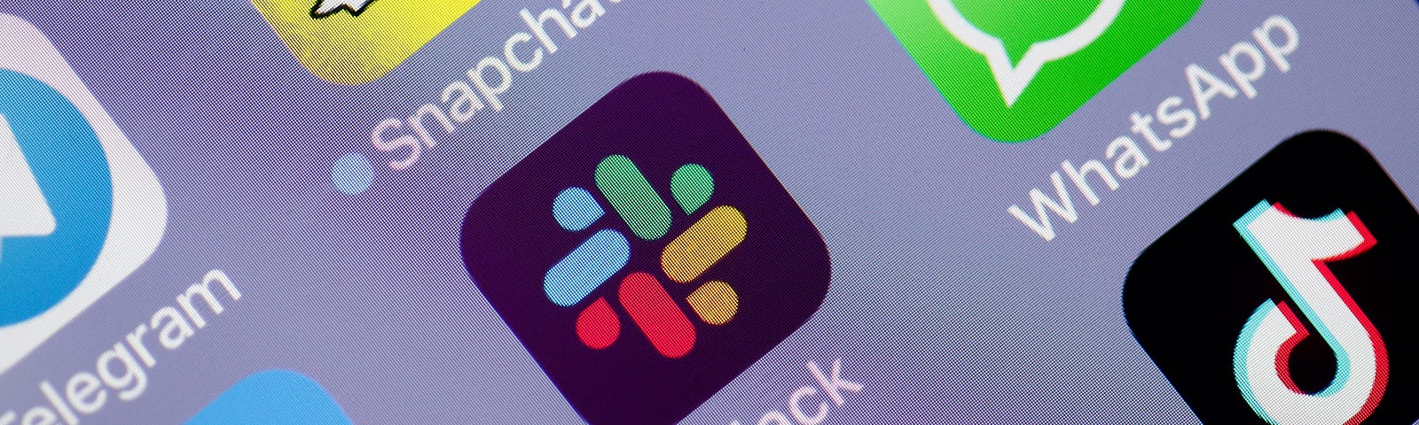 A close up of a phone display with various messaging and social media app icons, featuring the Slack app icon in the center.