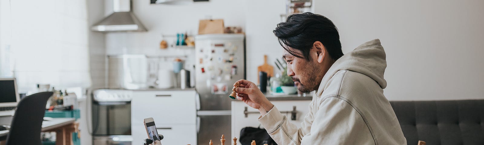 A man playing chess with a friend over a video call.