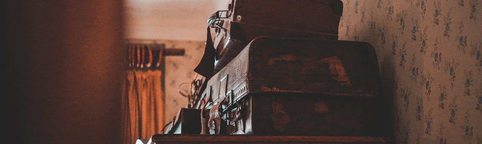 A wooden curio cabinet stacked with luggage, seen from the doorway of a bedroom.