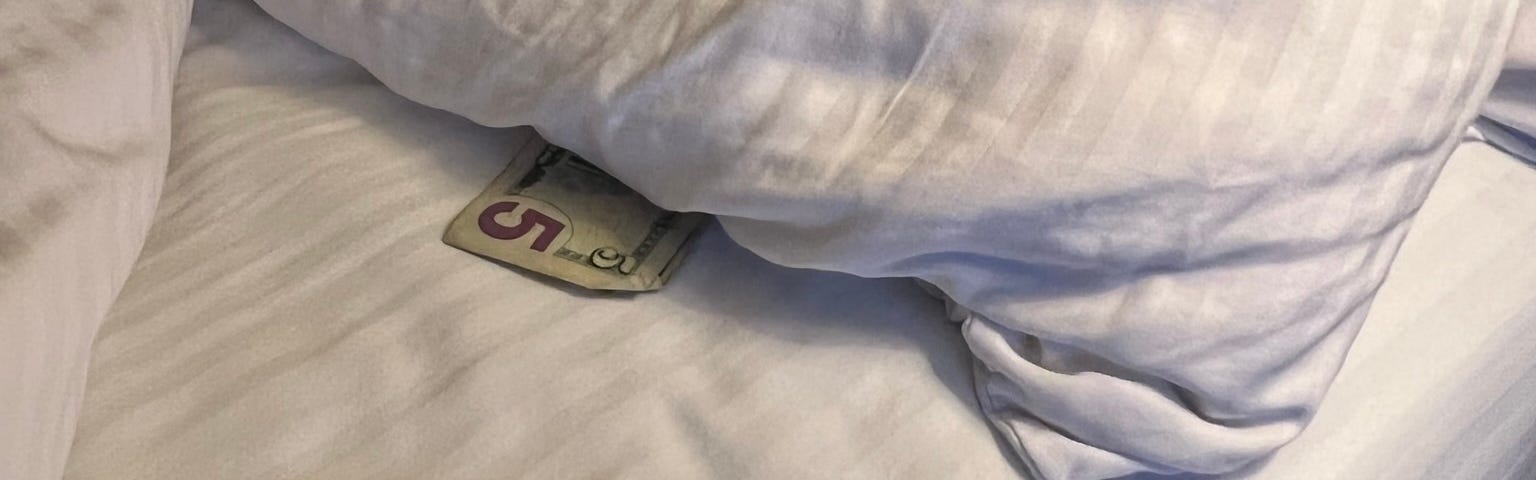 Photo of hotel bed with a tip for housekeeping under pillows.