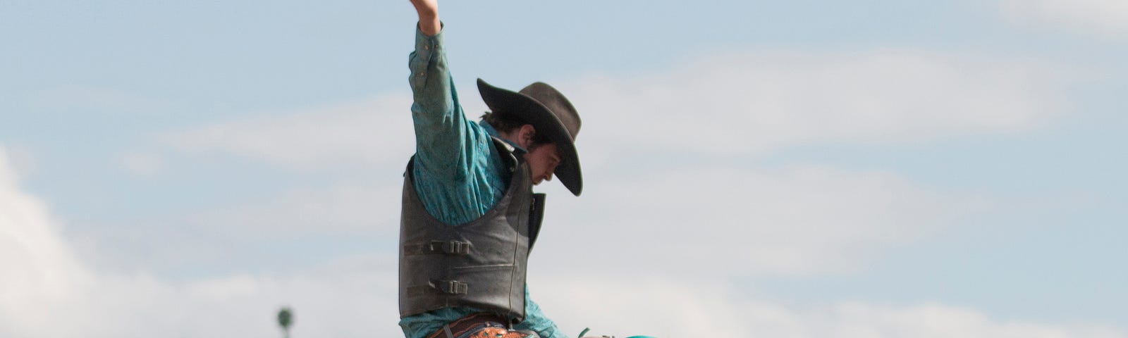 a man riding a bucking bronco in a rodeo competition