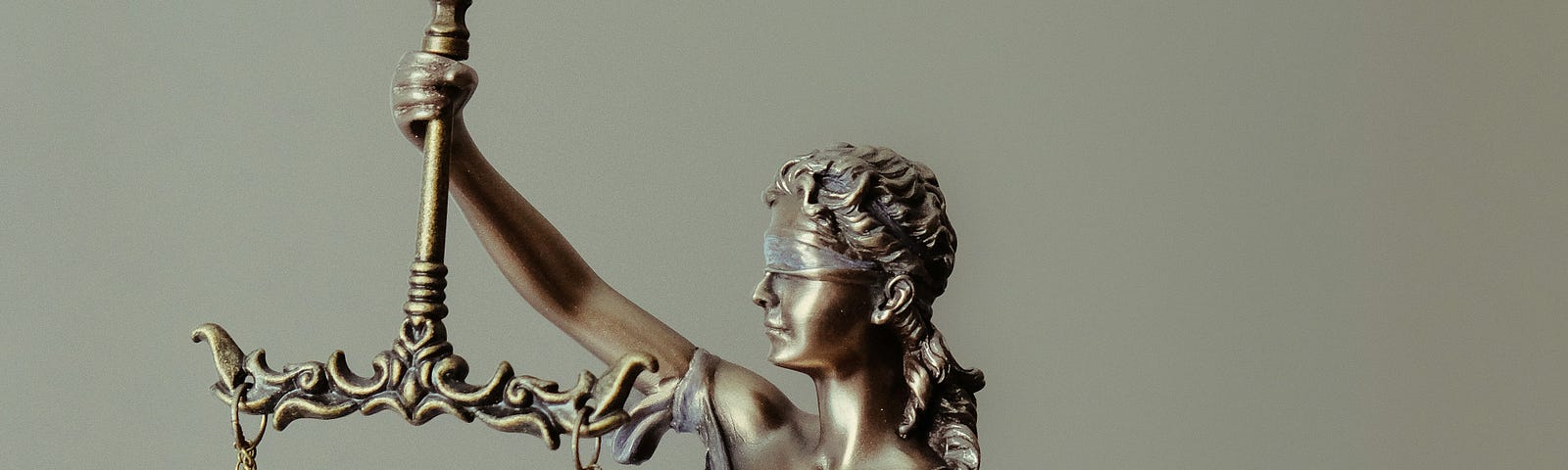 Sculpture of a blindfolded woman holding a sword in one hand and the scales of justice in the other.