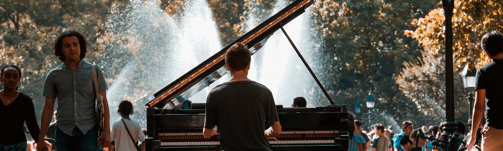 Rear view of a man playing piano in an outdoor park.