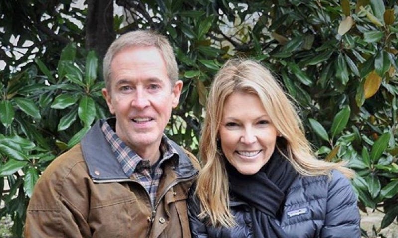 A middle-aged white man and woman (Andy Stanley and his wife) sitting on a stack of hay bales. he is wearing a brown jacket and she is wearing a blue jacket and gloves. They are holding hands and smiling at the camera.