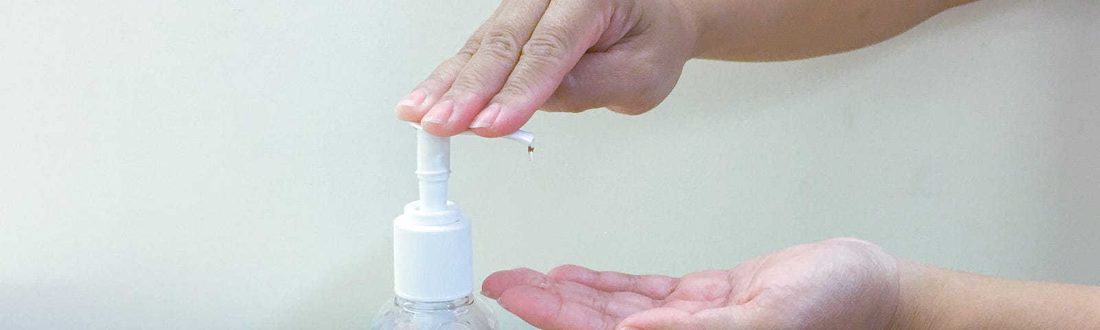 A photo of a person squirting hand sanitizer out of a bottle onto their hands.