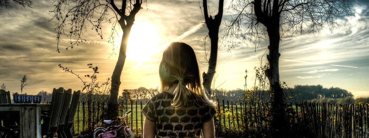 Young girl in backyard gazing into sunrise