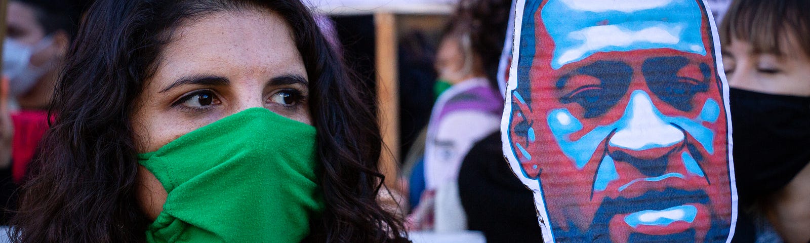 A woman wearing a face mask holds up a sign of George Floyd at a protest in Buenos Aires, Argentina.