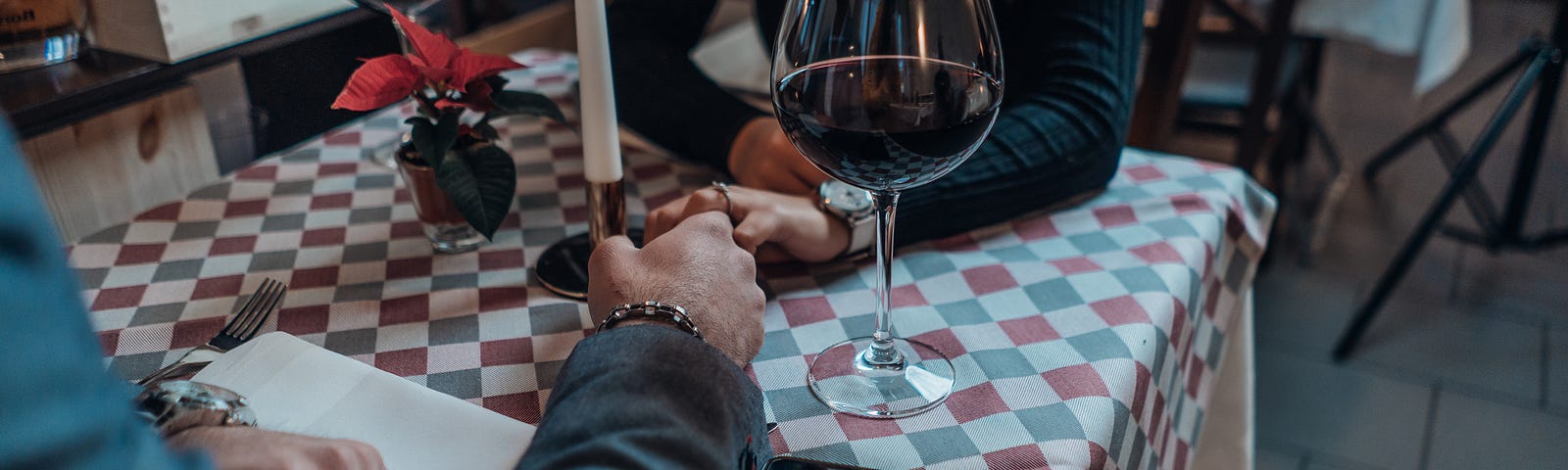 A couple holds hands at a restaurant, a candle and glass of wine between them. #love #dating #relationships #date