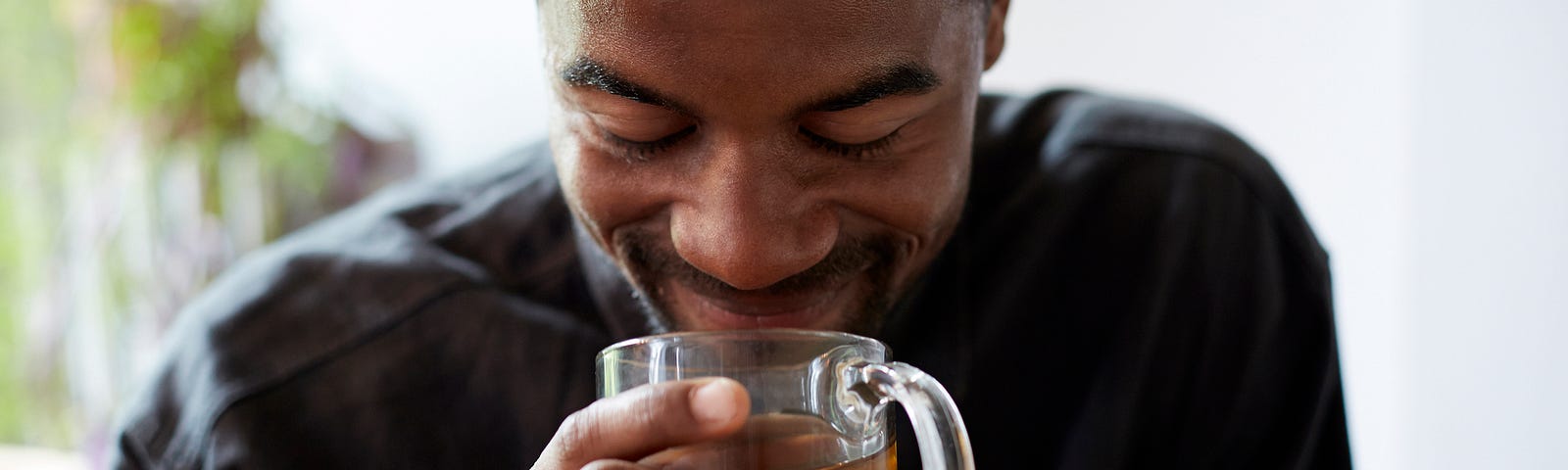 Black man smiling over a cup of tea.