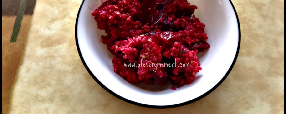 A bright red bowl of delicious roasted beet oatmeal on a colorful placemat