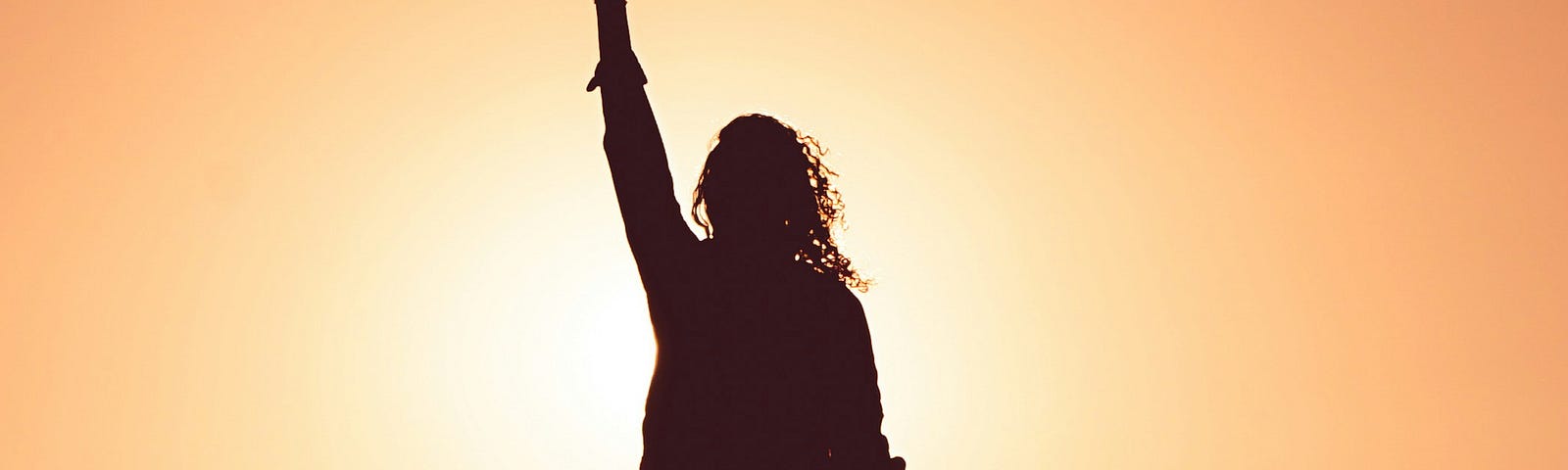 A silhouette of a person with hand and fist raised to the sky