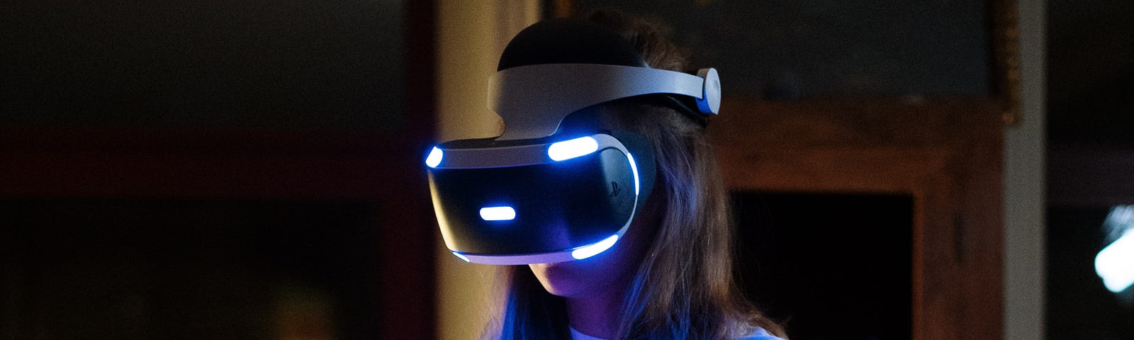A woman is standing in a room with a VR headset on. It is nighttime.
