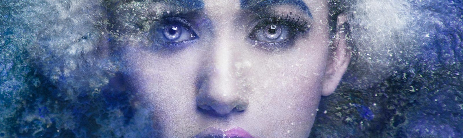 A woman with light blue eyes and purple lipstick poses with a shocked expression, the cool tones and frosted effects of the shot indicate she’s encased beneath a sheet of ice.