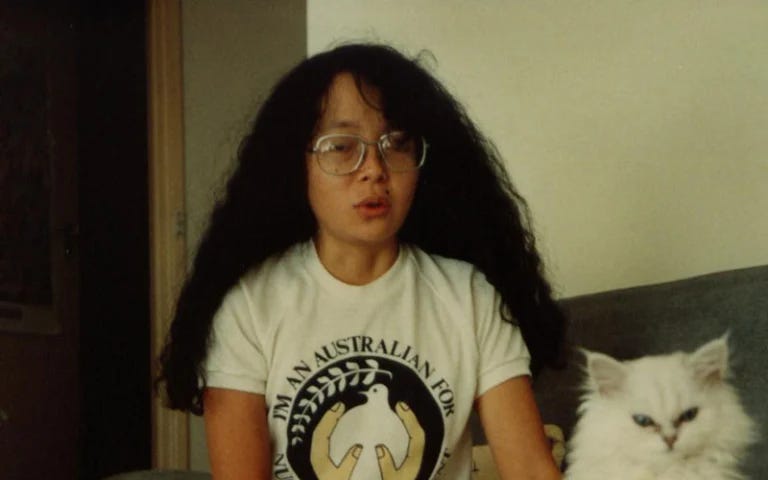 Girl with permed hair sitting next to a white cat