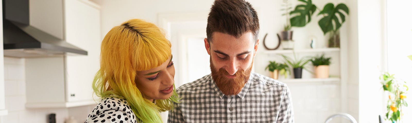 A couple in their kitchen looking at one of their phones.