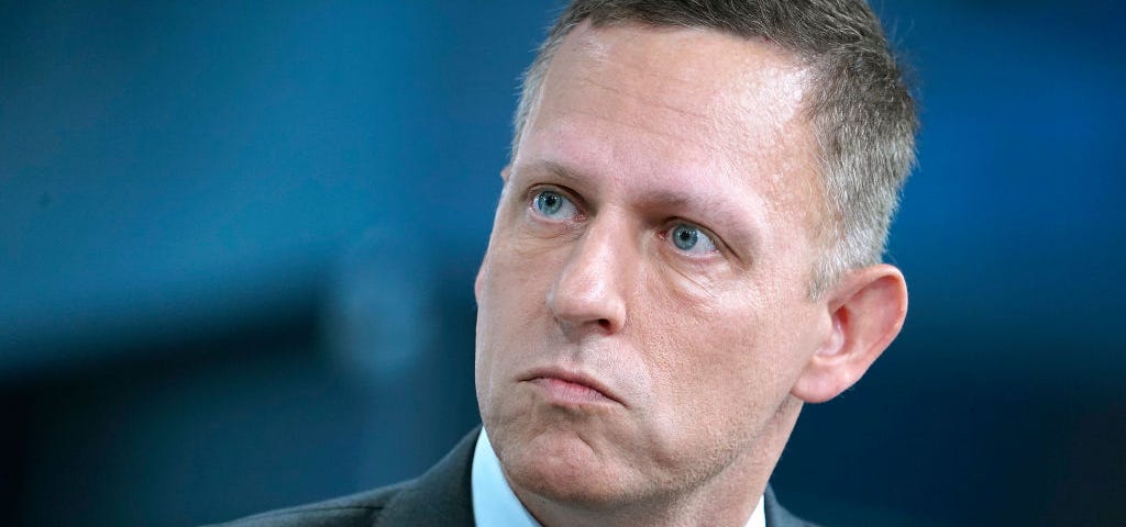 Closeup photo of Peter Thiel wearing a suit during an interview.