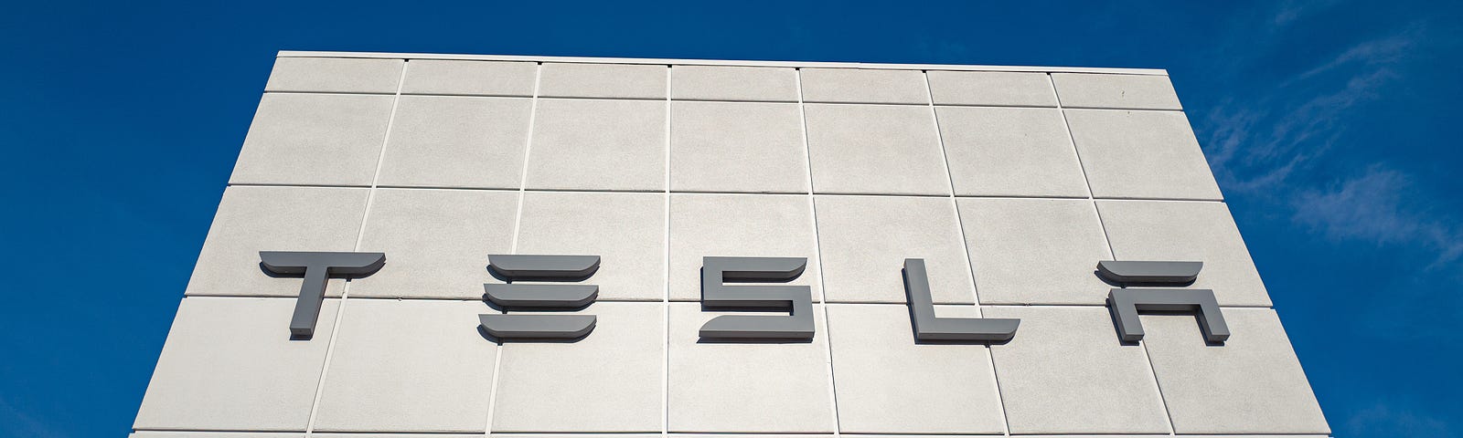 Low-angle view of the facade of Tesla Motors dealership with logo and sign in Pleasanton, California.